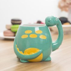 a ceramic teapot shaped like a turtle sitting on a table with cookies and doughnuts in the background