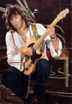 a man with long hair playing an electric guitar