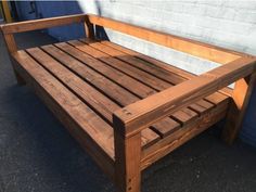 a wooden bench sitting in front of a white brick wall on a sidewalk next to a blue building