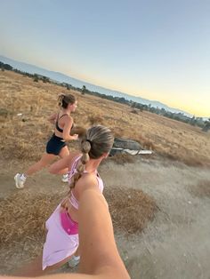 two women are running in the grass on a sunny day