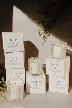 three candles sitting next to each other on top of a white table with greeting cards