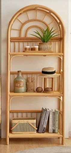 a bamboo shelf with books and plants on it next to a wicker chair in a living room