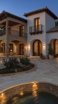 a large house with a hot tub in front of it at night, lit up by lights