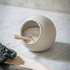 a white bowl filled with sea salt next to a cutting board