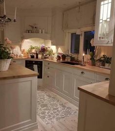 a kitchen with white cabinets and wooden counter tops next to a window filled with flowers