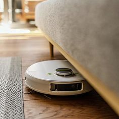 a robot vacuum on the floor next to a couch