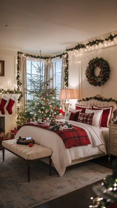 a bedroom decorated for christmas with lights on the tree and stockings hanging from the window