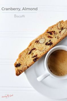 a white plate topped with a piece of cake next to a cup of coffee