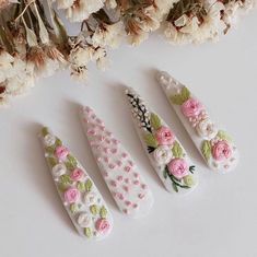 three small flowers are sitting next to each other on a white surface with dried flowers in the background