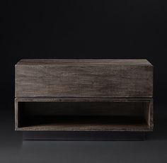 a wooden shelf sitting on top of a black floor in front of a dark wall