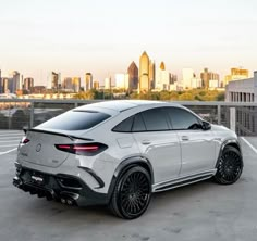 the rear end of a white mercedes suv parked in front of a cityscape