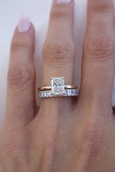 a woman's hand with a diamond ring on top of her finger and the other hand holding an engagement ring