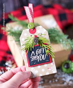 someone is holding up a gift tag with a pine cone on it and the tag says, a gift for you