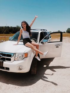 a woman is sitting on the hood of a white truck and posing for a photo