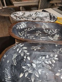 three wooden trays with painted designs on them sitting on top of a table in a room