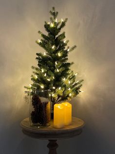 a small christmas tree sitting on top of a table next to two lit candle holders