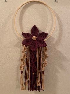 a crocheted flower hanging from a hoop with tassels on the end