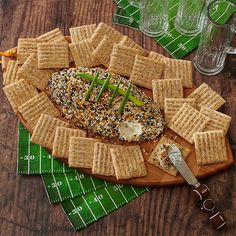 a platter with crackers and cheese on it next to a glass of water