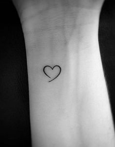 a heart tattoo on the wrist with a small black line in the shape of a heart