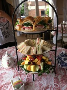 three tiered trays filled with sandwiches and fruit