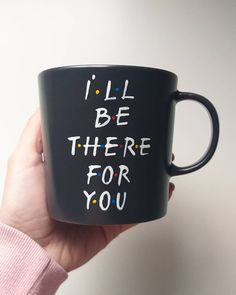 a hand holding a black coffee mug with i'll be there for you written on it