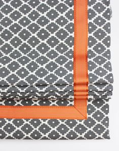 an orange ribbon is tied to the side of a gray and white patterned sheet set