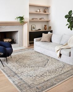 a living room with a couch, chair and rug on the floor in front of a fireplace