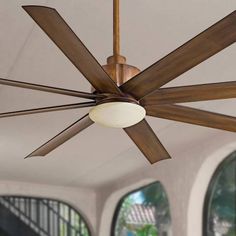 a ceiling fan that is hanging from the ceiling in a room with large windows and doors