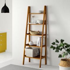 a wooden shelf with baskets and other items on it next to a yellow cabinet in a white room