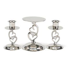 three silver candlesticks with hearts on them and two smaller ones sitting next to each other