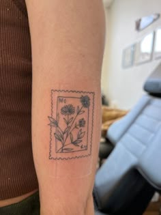 Photo of a tattoo that is inspired by a postage stamp. Flower Stamp Tattoo Ideas, Small Stamp Tattoo Ideas, Peony Stamp Tattoo, Honeysuckle Stamp Tattoo, Flowers In Box Tattoo, Hollyhocks Flowers Tattoo, Flower Polaroid Tattoo, Wildflower Stamp Tattoo, Flowers In A Frame Tattoo