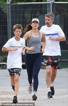 a man and two boys running in the street