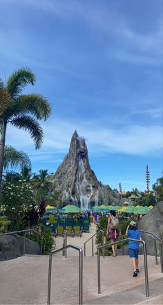 people are walking up stairs to the waterfall at disney's art of animation resort