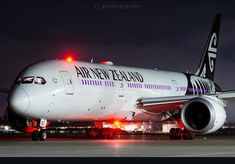 an air new zealand airplane on the tarmac at night with its lights turned on