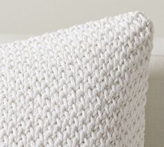 a white knitted pillow sitting on top of a couch