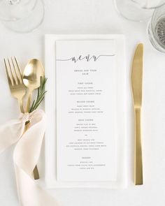 a table setting with gold utensils and menu cards