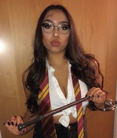 a woman dressed in harry potter costume holding a wand and looking at the camera while making a funny face