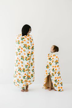 two people standing in front of a white wall wearing pajamas with oranges on them