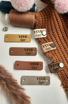 several different types of leather name tags on a white surface next to some brown feathers