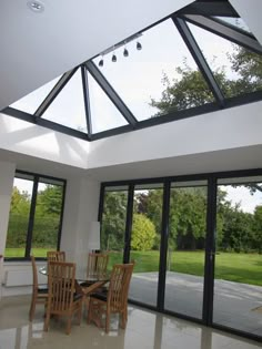 a dining room with glass walls and doors leading to the outside patio area is shown