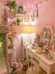 a room with pink walls and pictures on the wall, flowers in vases and other decorations