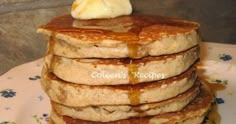 a stack of pancakes with syrup and butter on top are sitting on a floral plate