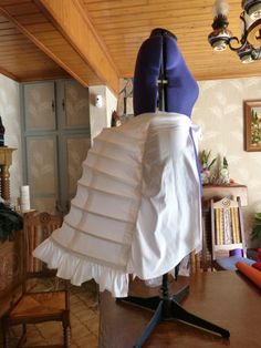 a white dress on a mannequin in a room with wooden floors and walls