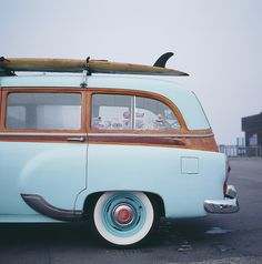 an old blue car with a surfboard on top