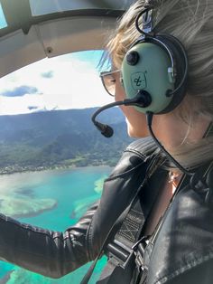 a woman wearing headphones is flying in an airplane over the ocean and coral reefs