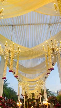 an outdoor wedding venue with chandeliers and flowers on the ceiling, decorated in gold