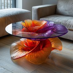 two colorful glass vases sitting on top of a wooden table next to a couch