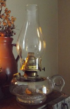 an old fashioned lamp sitting on top of a wooden table next to a vase with flowers in it