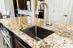 a kitchen with granite counter tops and an island sink in the middle of the room