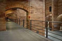 the walkway is made of brick and has metal railings on both sides that lead to an arched doorway